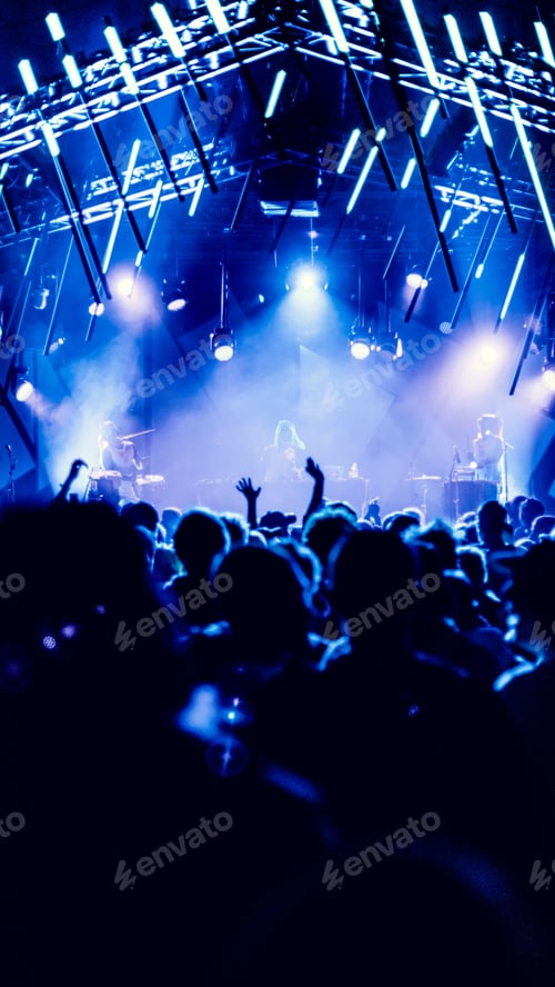 Preview: Vertical shot of people from back during the Roskilde Festival, Denmark in a hall with blue lights