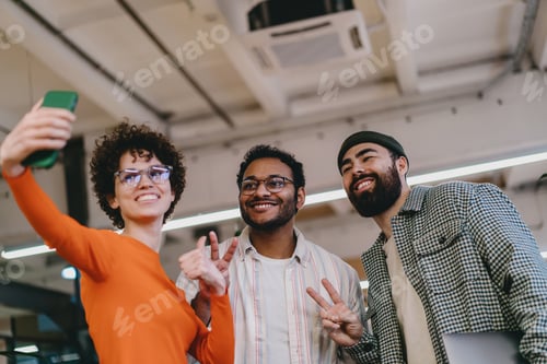 Preview: Cheerful multiethnic friends taking selfie together in office