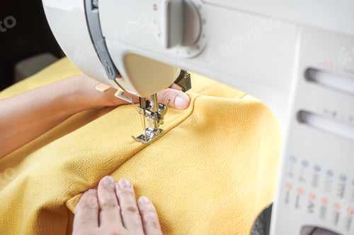 Preview: Tailor Hands Stitching Yellow Fabric On Modern Sewing Machine At Workplace In Atelier