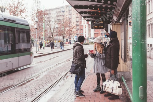 Preview: three friends waiting bus at bus station outdoor