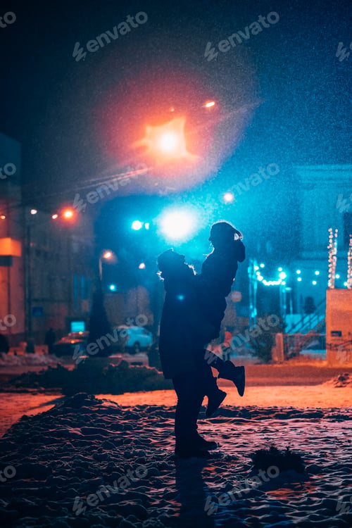 Preview: Young adult couple in each other's arms on snow covered street