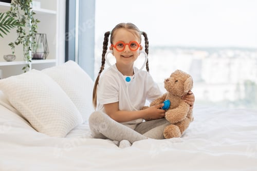 Preview: Cheerful girl in funny glasses treating favorite teddy bear