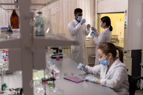 Preview: Group of young scientists working with fluids in flasks
