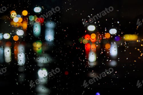Preview: Rain drops on window with road light bokeh city in night rainy season