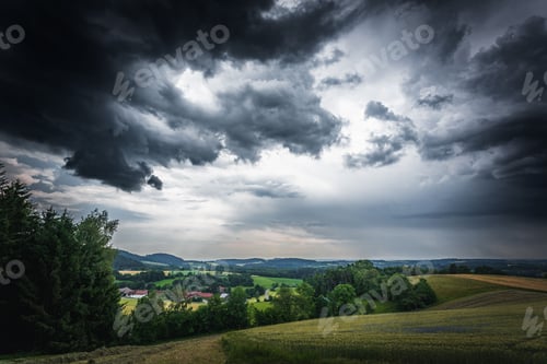 Preview: Dramatic thunderclouds over a field with green trees