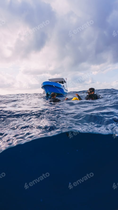 Preview: split shot of two divers on the surface next to a boat