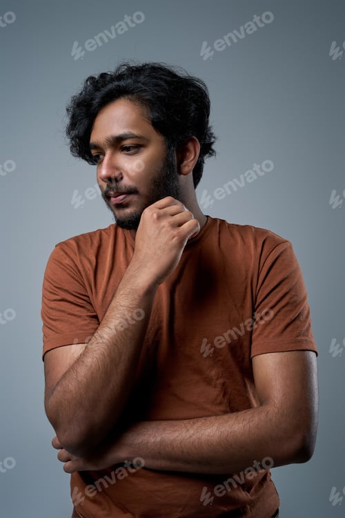 Preview: Serious hindu with modern haristyle poses in studio looking at camera
