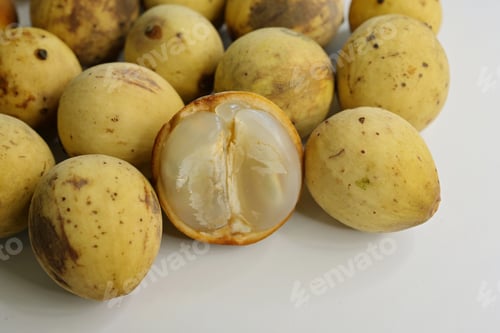 Preview: Translucent lobes of a langsat fruit with skin removed & whole fruits on white background