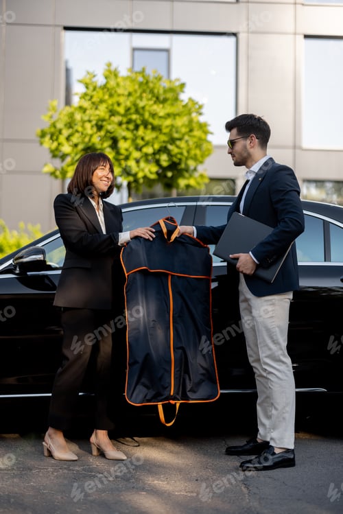 Preview: Female chauffeur gives a businessman his suit, after a business trip by car