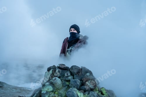 Preview: A man walking behind the steaming fumaroles at Hverir or Namafjall geothermal park in winter