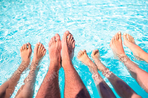 Preview: Close up of four people's legs by pool side