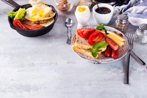 Preview: English breakfast. Fried eggs, sausages, toasts, tomatoes on stone table.