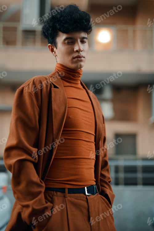 Preview: Young man in a stylish brown outfit standing confidently in an urban environment