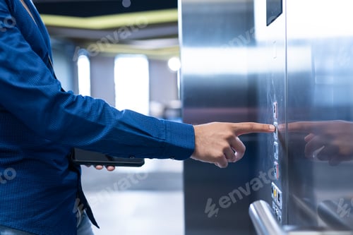 Preview: Pressing elevator button, person in blue shirt holding tablet in modern office