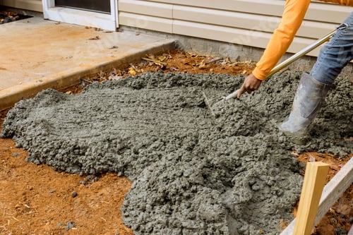 Preview: A construction worker pours cement on the side of the house to create a new sidewalk that will