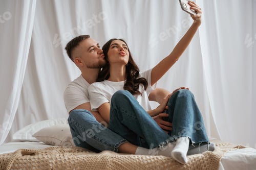 Preview: Affectionate Young Couple Taking Selfie in Bed