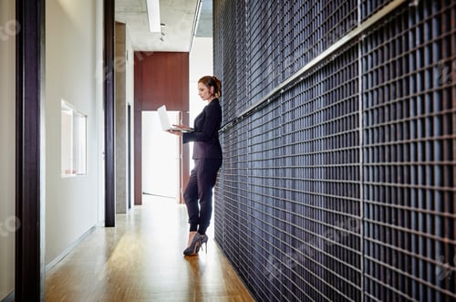 Preview: Businesswoman standing on office floor using laptop
