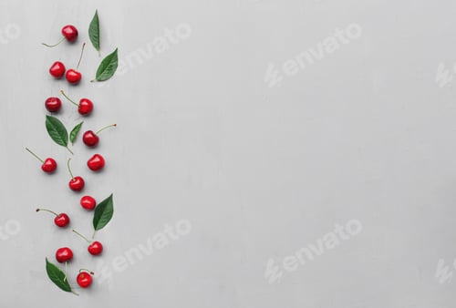 Preview: Top view on gray concrete background, sweet cherry berries, green leaves