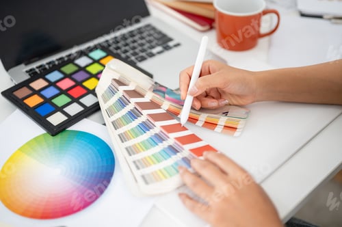 Preview: Close up of a hand pointing a stylus at a color palette. Designer choosing or picking a color.