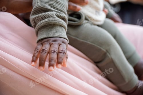Preview: Closeup of an African American mum's hands holding her baby on her knees