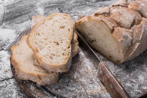 Preview: Bakery concept background. Knife cutting bread loaf slices