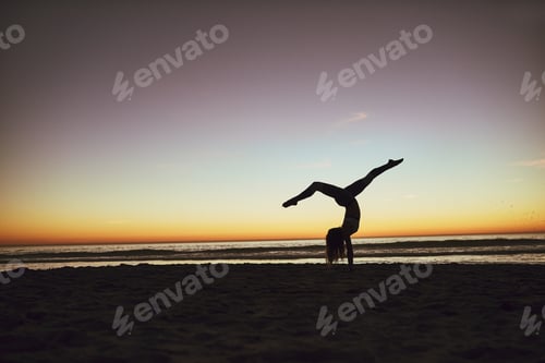 Preview: Shot of an athletic young woman practicing yoga on the beach