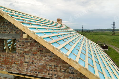 Preview: Aerial view of a brick house with wooden roof frame under construction