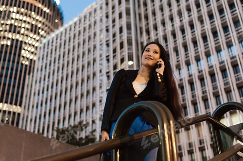 Preview: Ethnic businesswoman speaking on smartphone in downtown