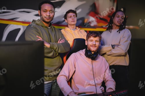 Preview: Smiling multiethnic men looking at camera near computer monitor in cyber club