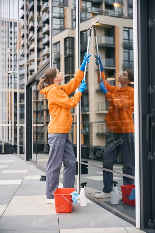 Preview: Pretty cleaning company worker washes windows of the office center