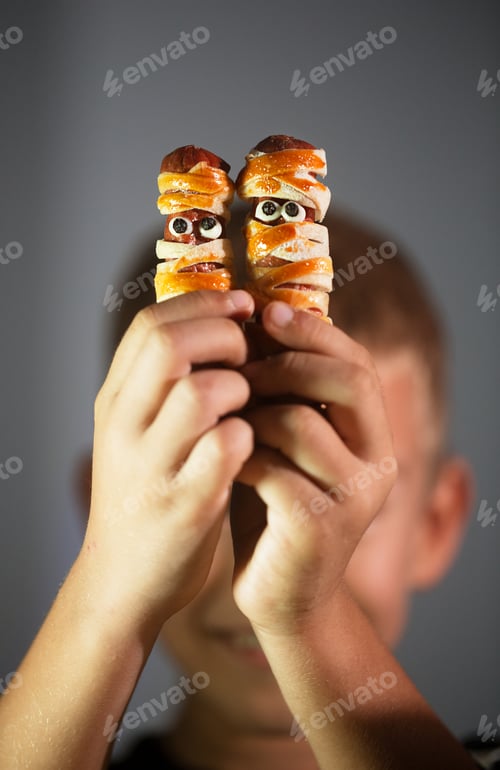 Preview: Boy holds Halloween snacks made from dough and sausage