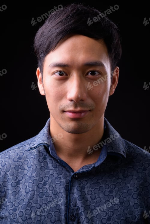 Preview: Young handsome Asian businessman against black background