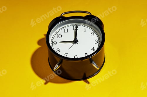 Preview: Black alarm clock with a hard shadow on a yellow background
