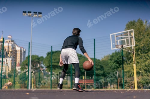 Preview: a sports ground basketball field active recreation guy in white shorts and black t-shirt plays