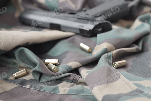 Preview: 9mm bullets and pistol lie on folded camouflage green fabric. A
