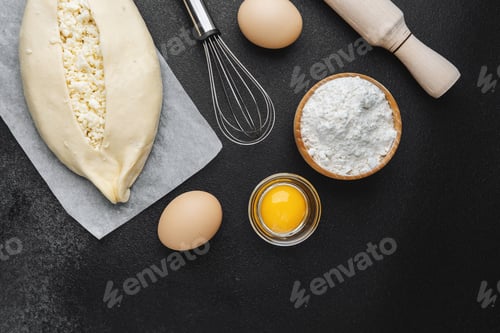 Preview: Khachapuri with cheese and yolk on parchment and dark kitchen table