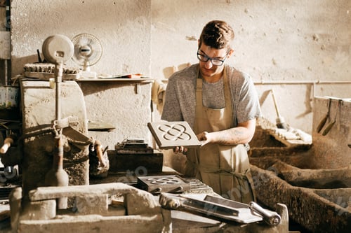 Preview: Young Man Displaying Cement Tile With Barcelonas Famous Panot Pattern in a Workshop During Daytime