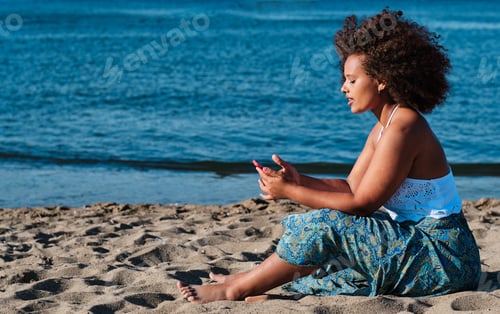 Preview: young curvy real woman at the beach with smartphone