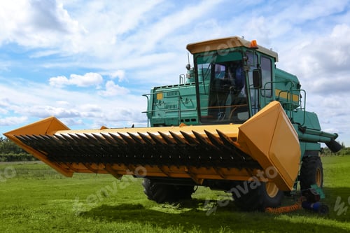 Preview: Modern combine harvester on green lawn with fresh grass