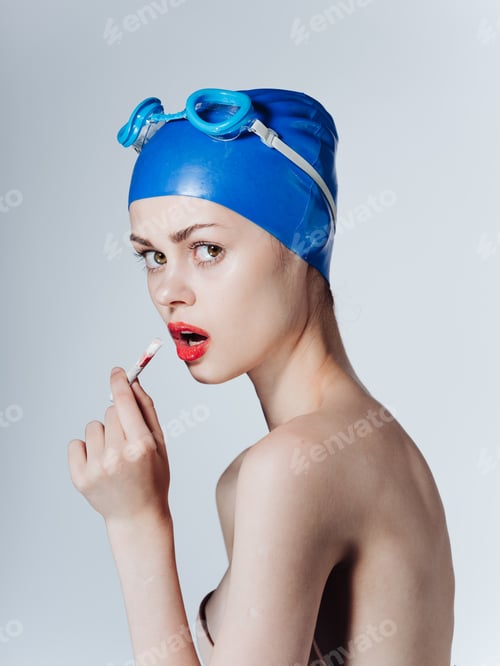 Preview: Woman swimmer in a blue swimming cap is smoking on a light background