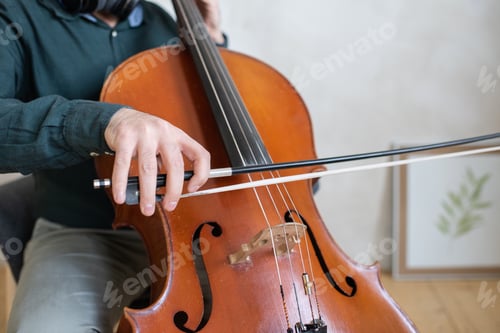 Preview: Hand of young cello player gliding fiddlestick across strings