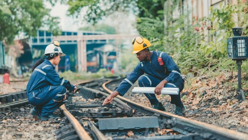 Preview: Engineer in safety gear inspects railway track for wear and alignment, ensuring safety standards.
