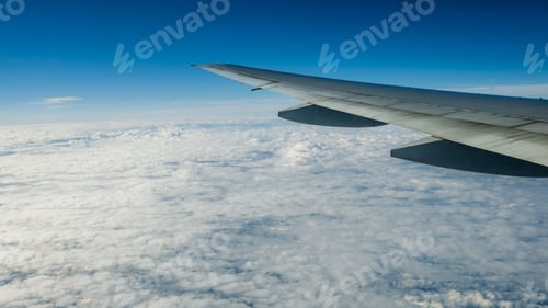 Preview: Close up of window with airplane wing. Beautiful cloudscape with clear blue sky.