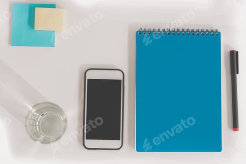 Preview: Top view of smartphone with blank screen, notebook with pen, glass of water and sticky notes