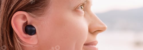 Preview: Woman using wireless earpieces, seaside on the background