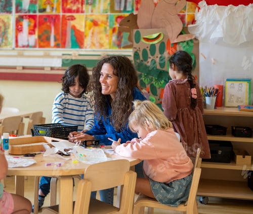Preview: Happy encouraging teacher speaking to her class, young group of children listening to their lesson