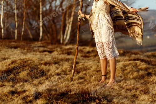 Preview: woman legs in native indian american boho dress walking in windy sunny mountains