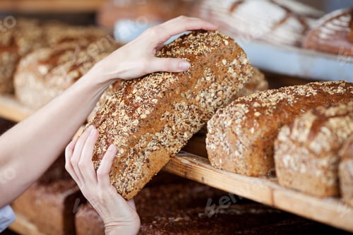 Preview: Cropped Image Of Female Bakery Worker'S Hands Removing Whole Grain Bread Loaf From Shelves