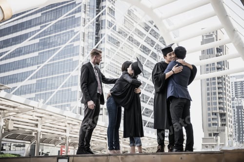 Preview: Happy international students and bachelor gowns with diplomas.