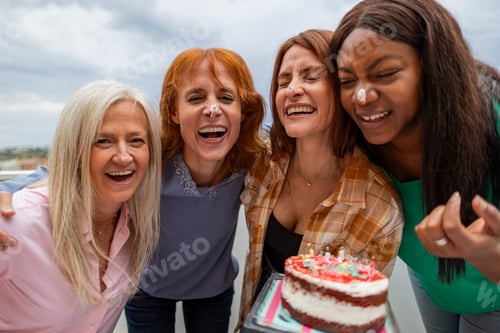 Preview: Four women having fun celebrating birthday with cake